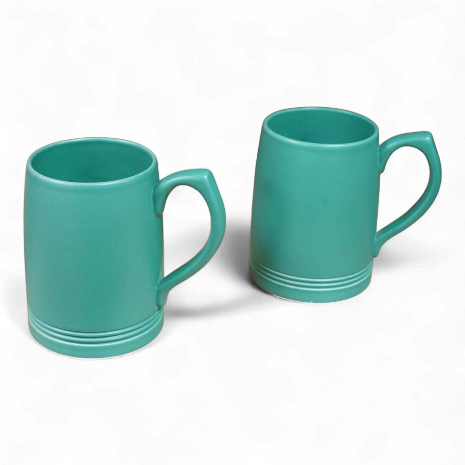 A pair of Keith Murray for Wedgwood green monochrome tankards, 12cm high